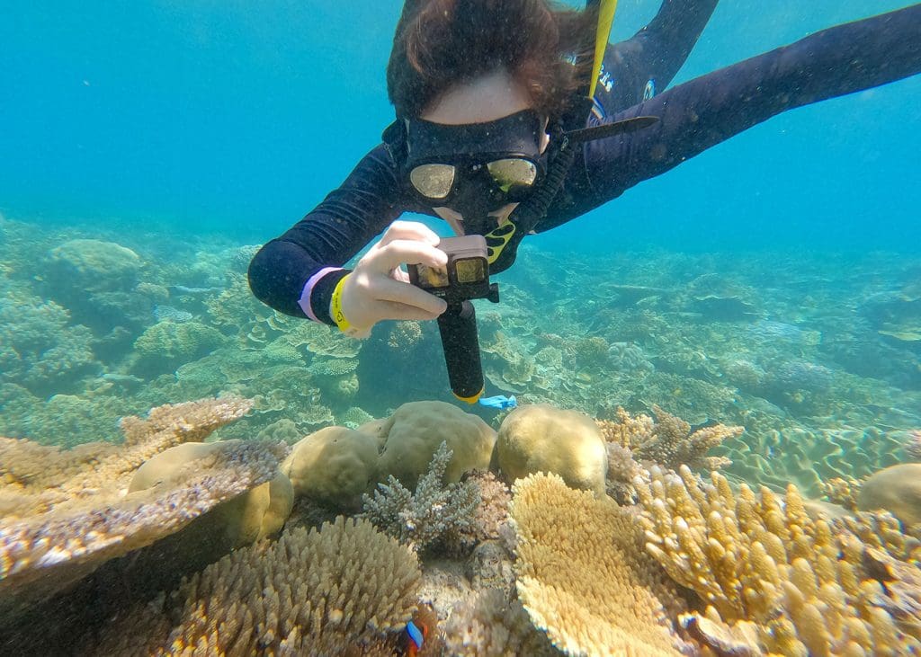 Teen snorkelling on the Great Barrier Reef using a rental underwater camera at Moore Reef