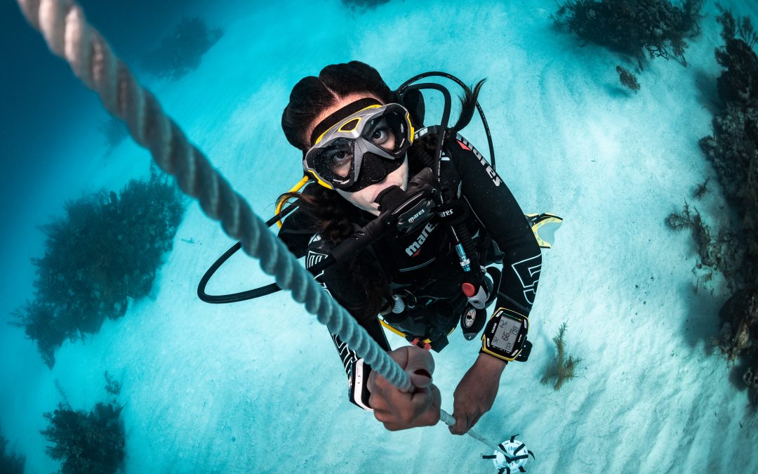 Scuba diver making a controlled ascent up the descent line over coral on the Great Barrier Reef