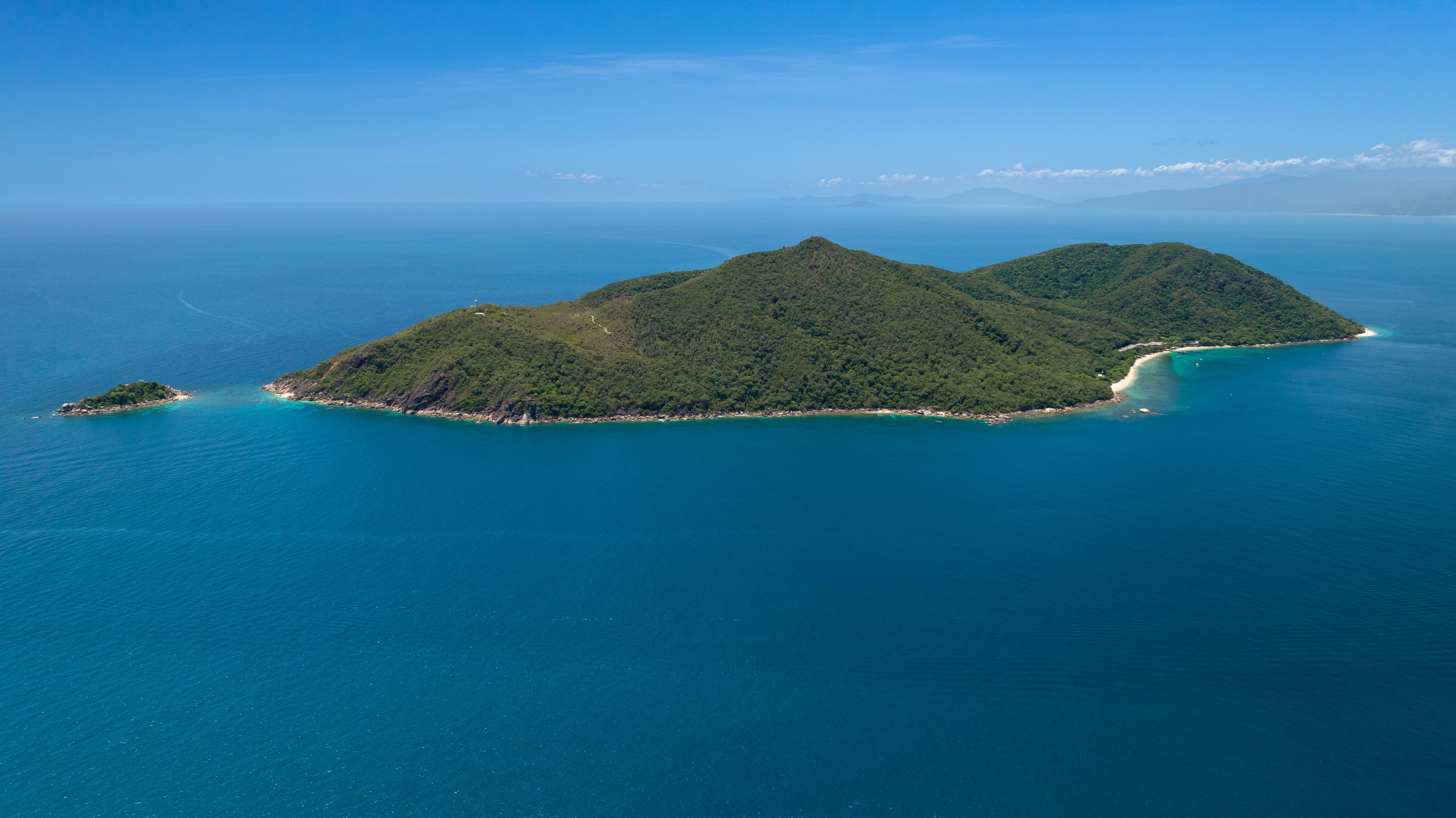 Aerial view of Fitzroy Island's forested peak and coral sand beaches surrounded by the Great Barrier Reef
